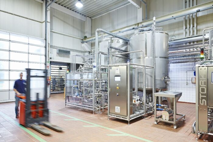 man operating forklift in front of dairy processing equipment